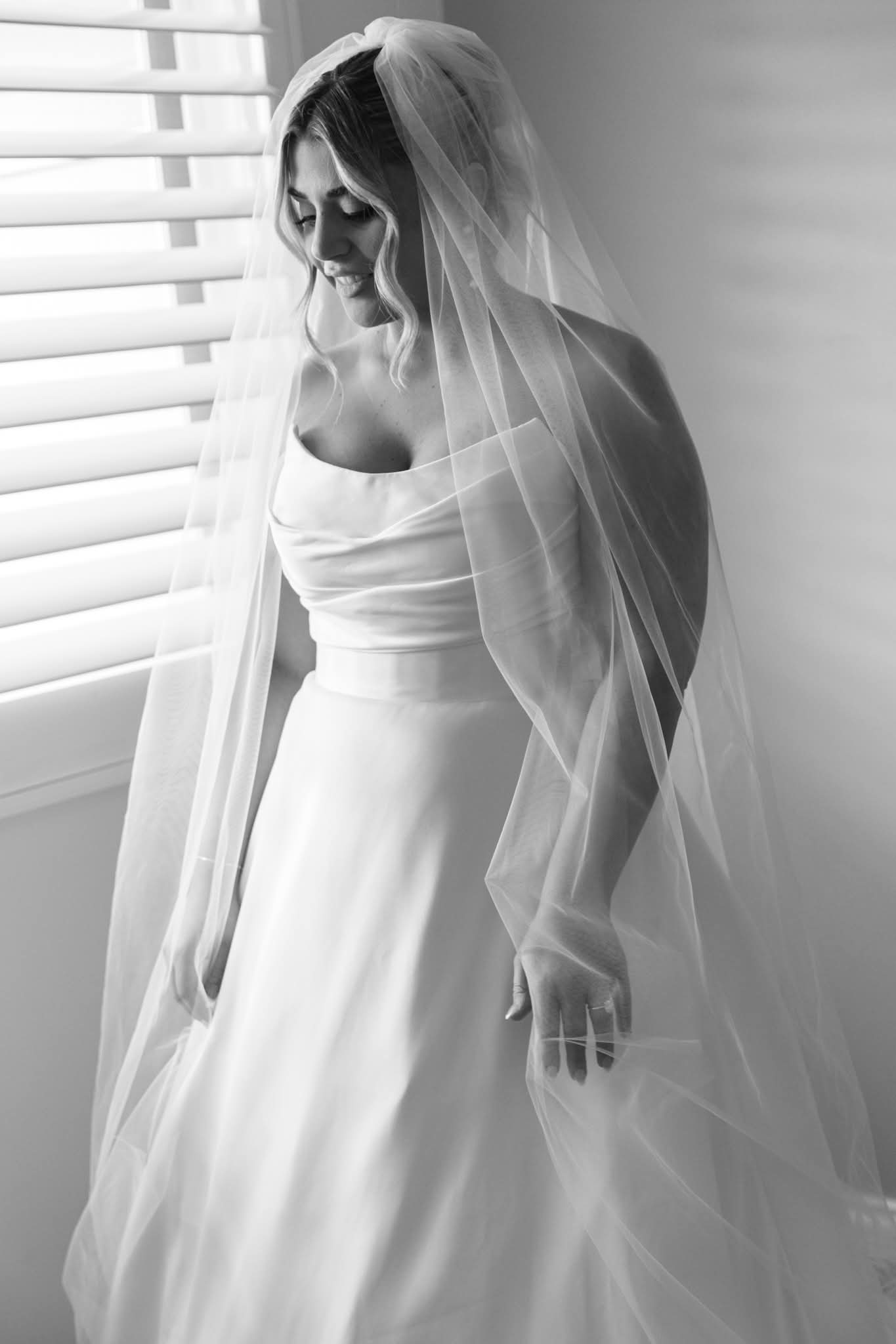 Bride with veil by window in black and white